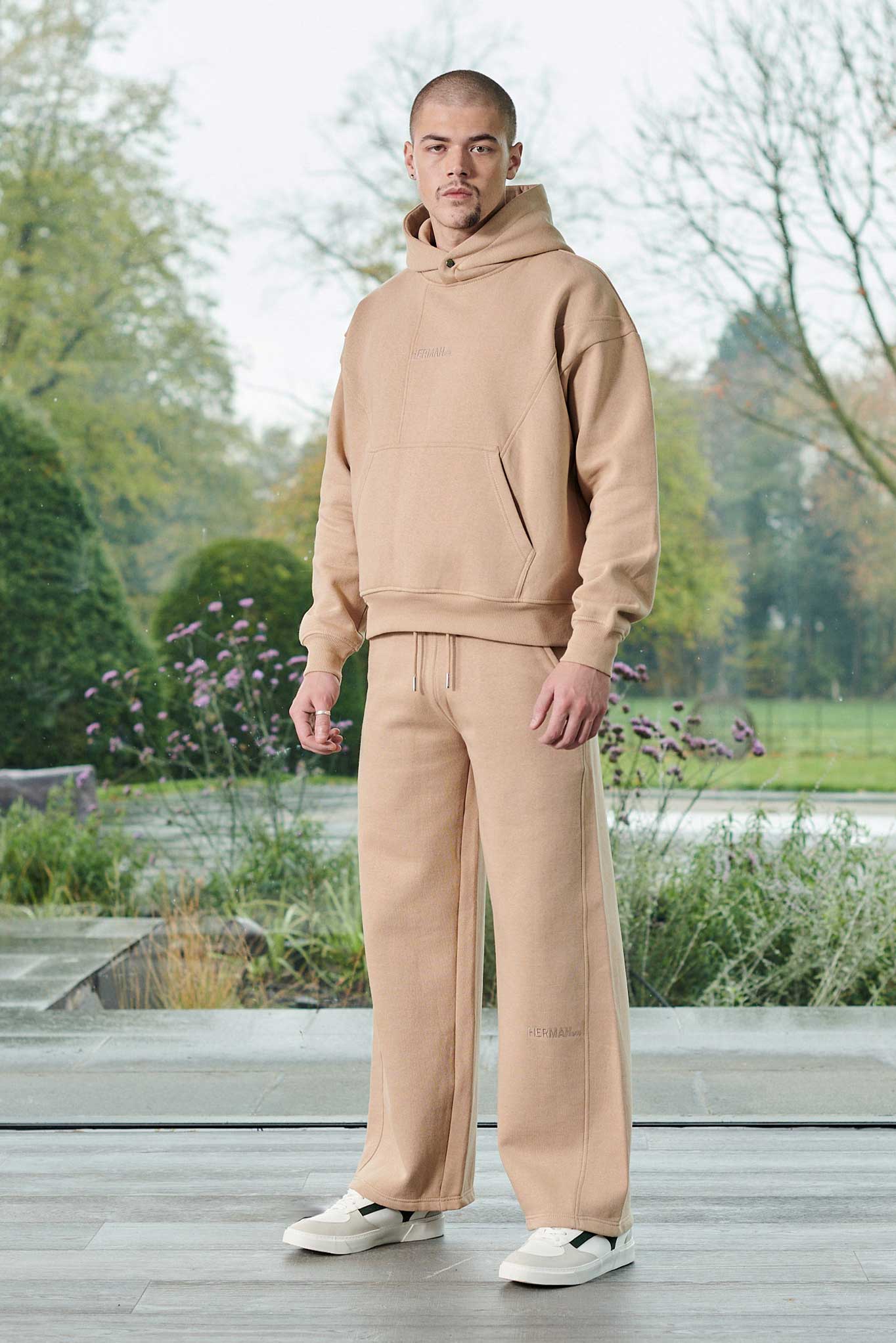 Front view of model styled in a beige pullover hoodie men outfit with matching trousers
