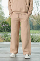 Close-up of the men's beige wide-leg joggers with embroidered logo detail