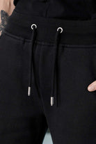 Detailed close up of the adjustable drawstring waistband on black tech fleece shorts