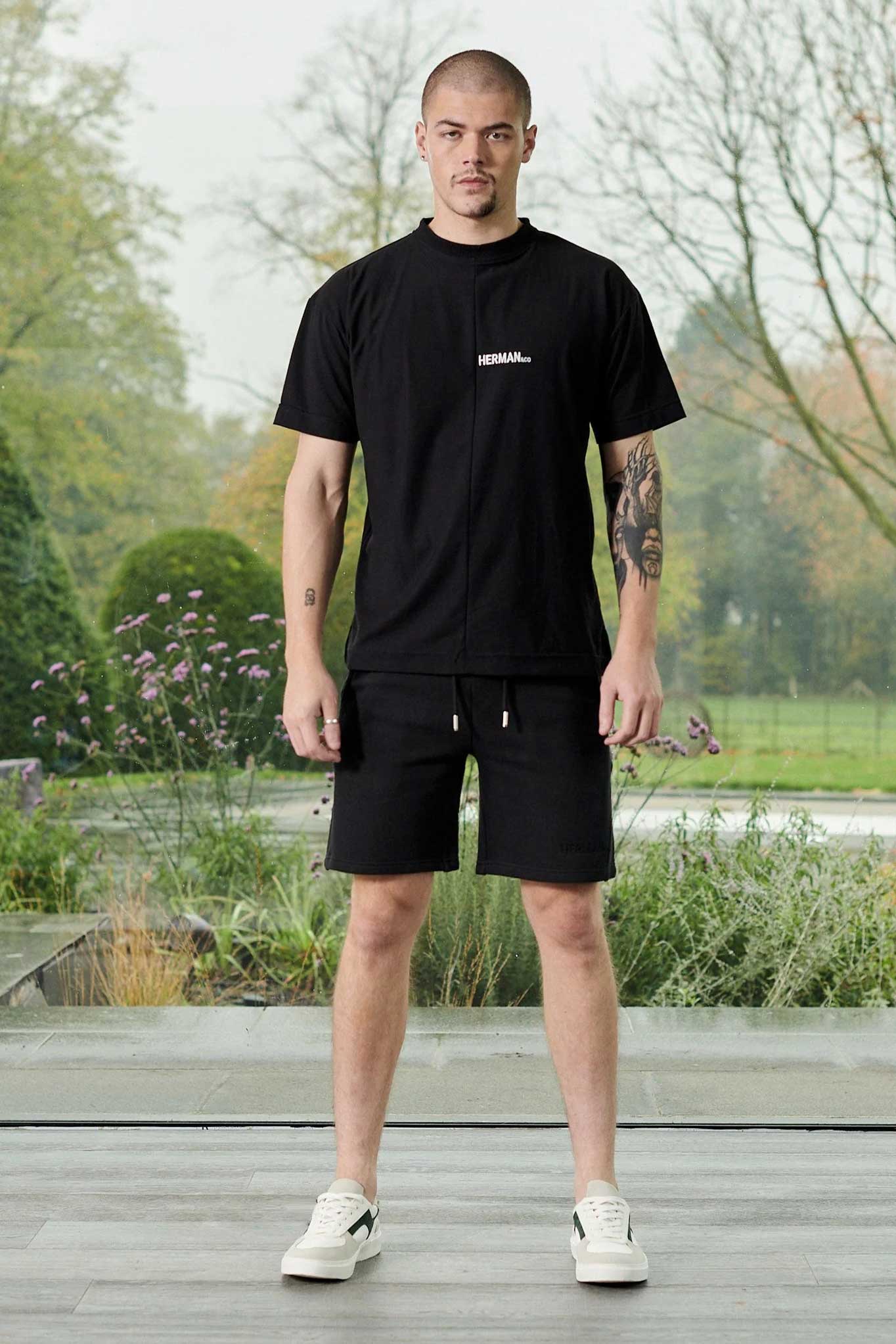 Front view of model wearing black tech fleece shorts men in a relaxed standing pose