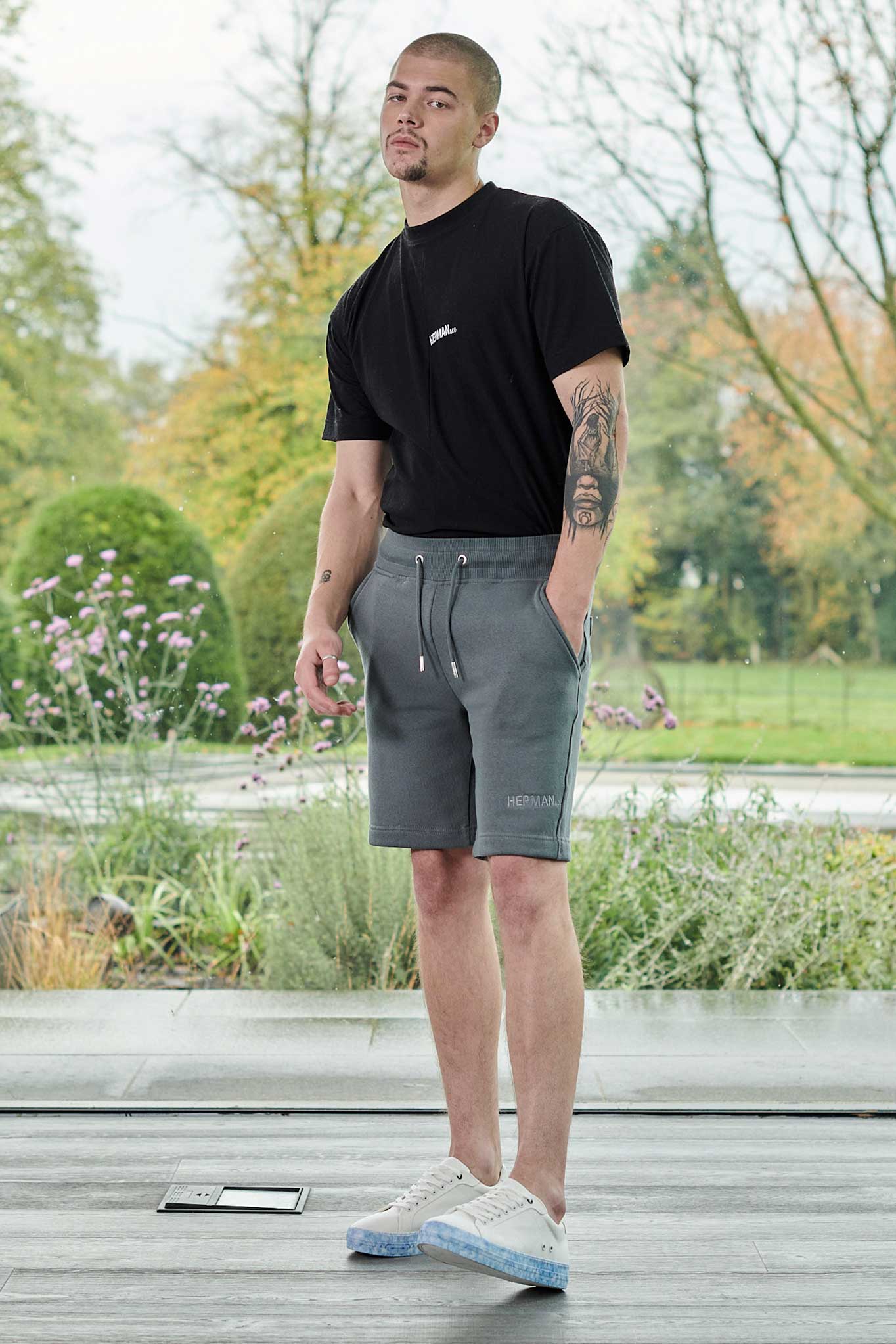 Front view of model wearing mens tech fleece shorts in cool grey with black tee