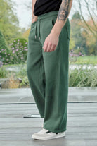 Side profile of a model wearing the men's dark green wide-leg joggers