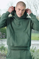 Close up of model adjusting the hood on mens dark green hoodie