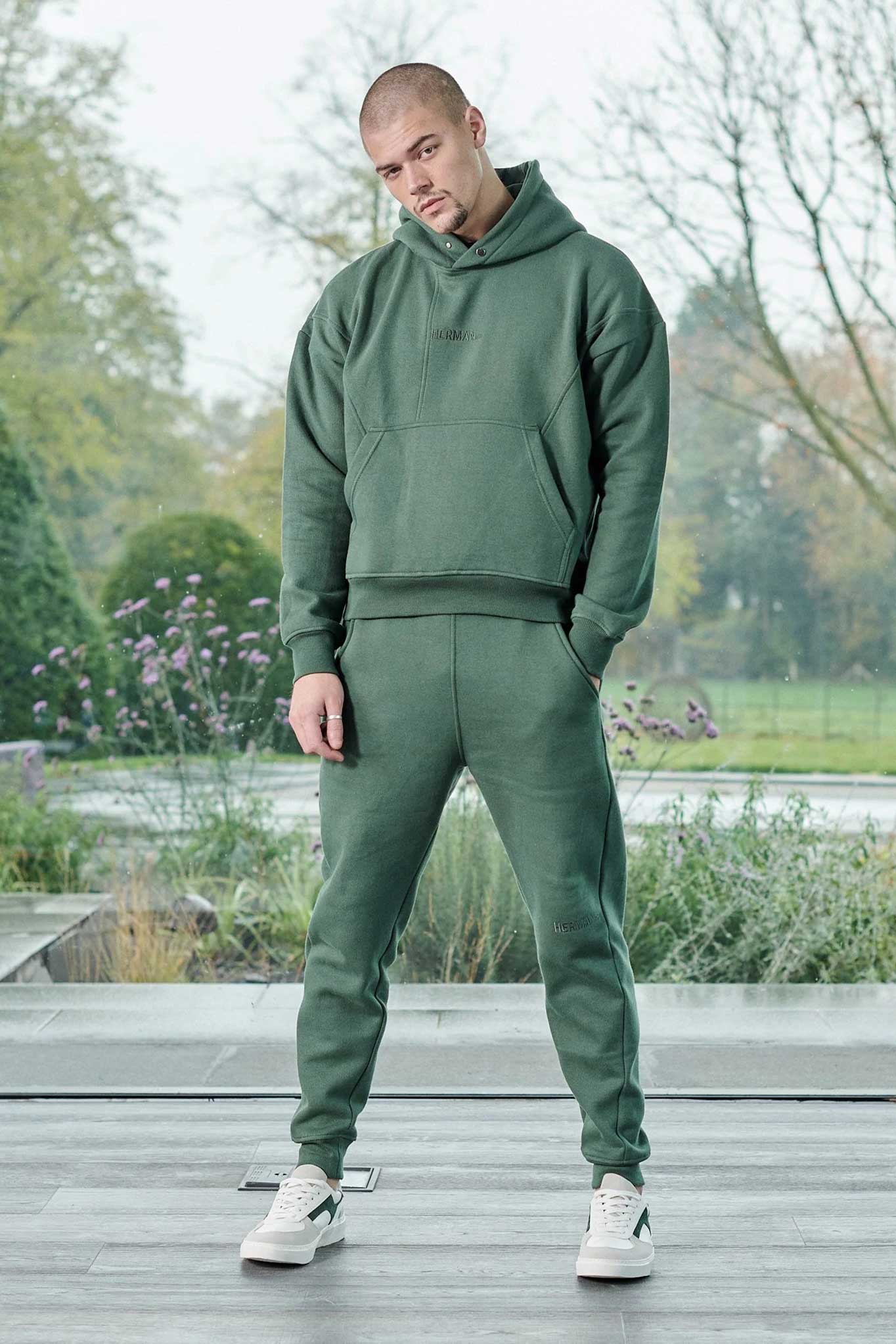 Full length view of model wearing dark green joggers mens as part of a tracksuit