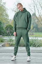 Full length view of model wearing dark green joggers mens as part of a tracksuit