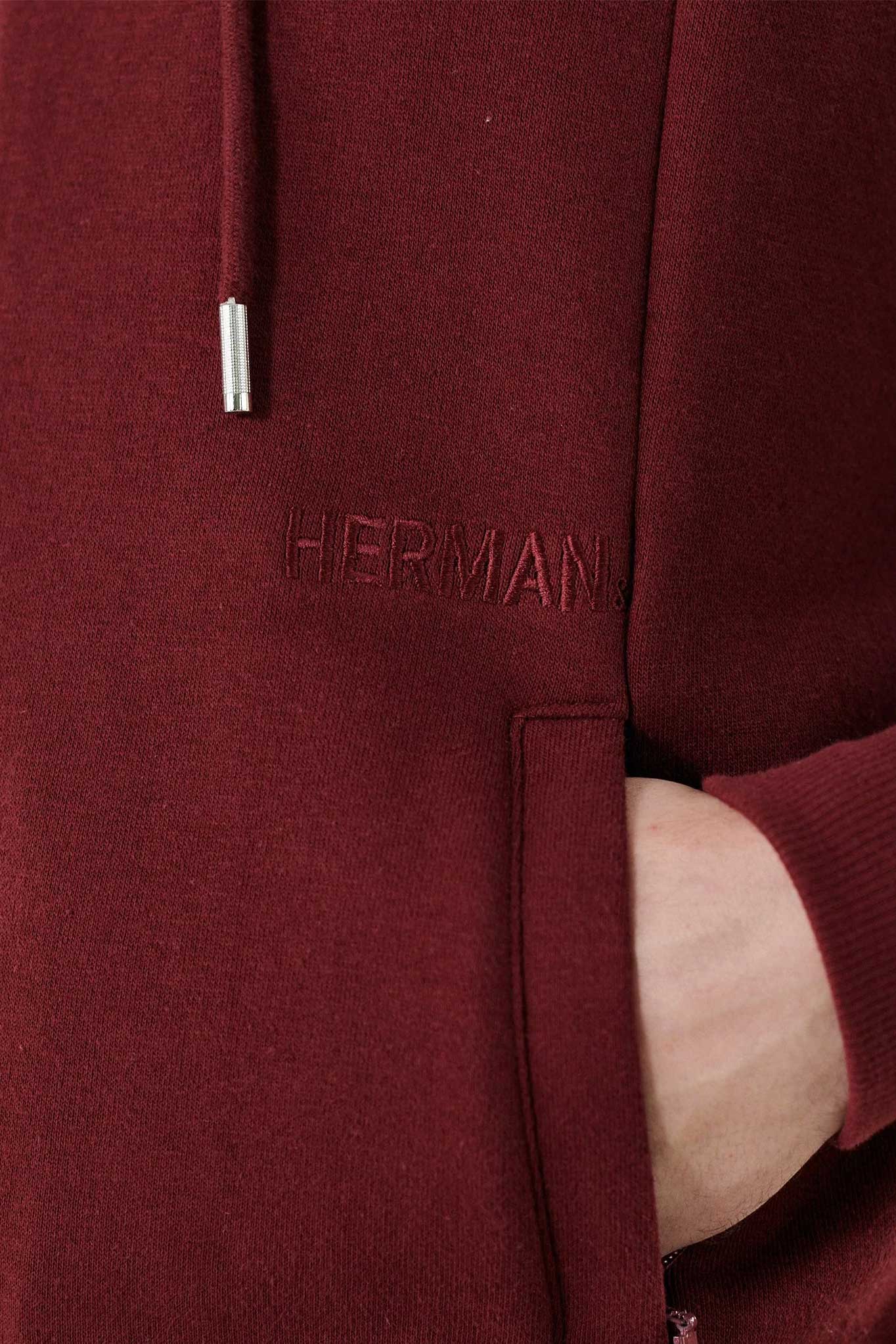 Close-up of the pocket and tonal logo on the men's maroon zip-up hoodie