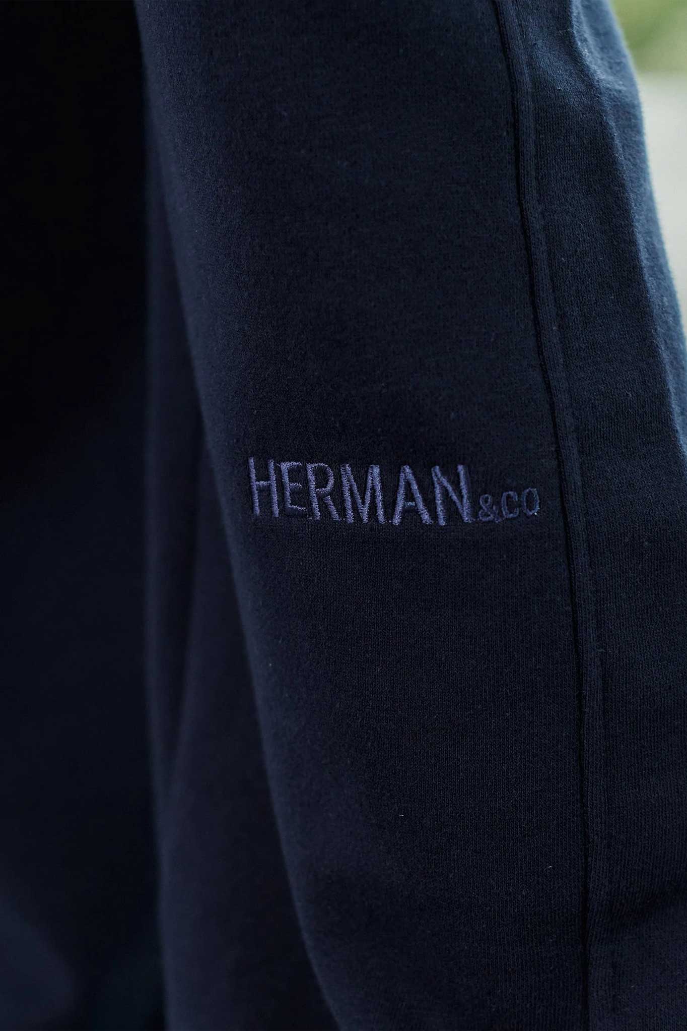 Close-up of the tonal embroidered logo on the men's navy jogger pants.
