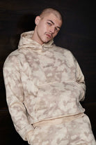 Model wearing a stylish beige mens tie dye hoodie in streetwear style