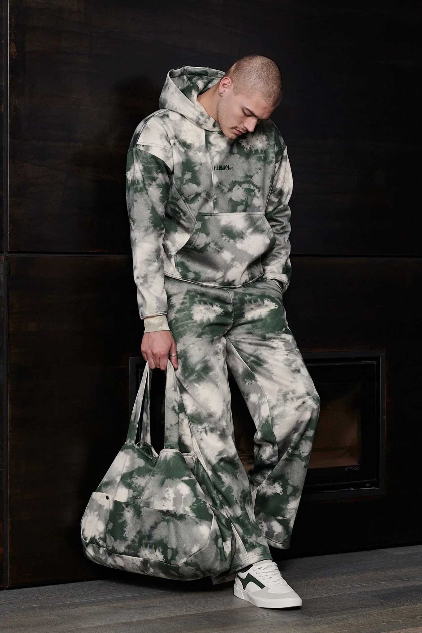 Front view of mens tie dye hoodie in green worn with matching trousers and bag