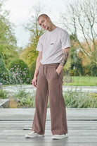 Full view of a model in the men's wide-leg joggers in brown