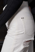 Side view showing the hip and distressed details on the off-white jeans.