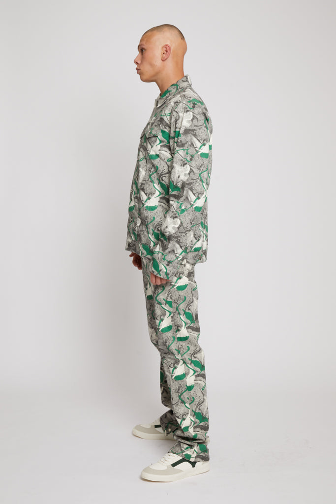 Side profile of a model showing the full psychedelic printed men's jacket and jeans set.