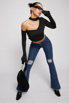 A model styled in the dark wash distressed flare jeans with a black top and bag.