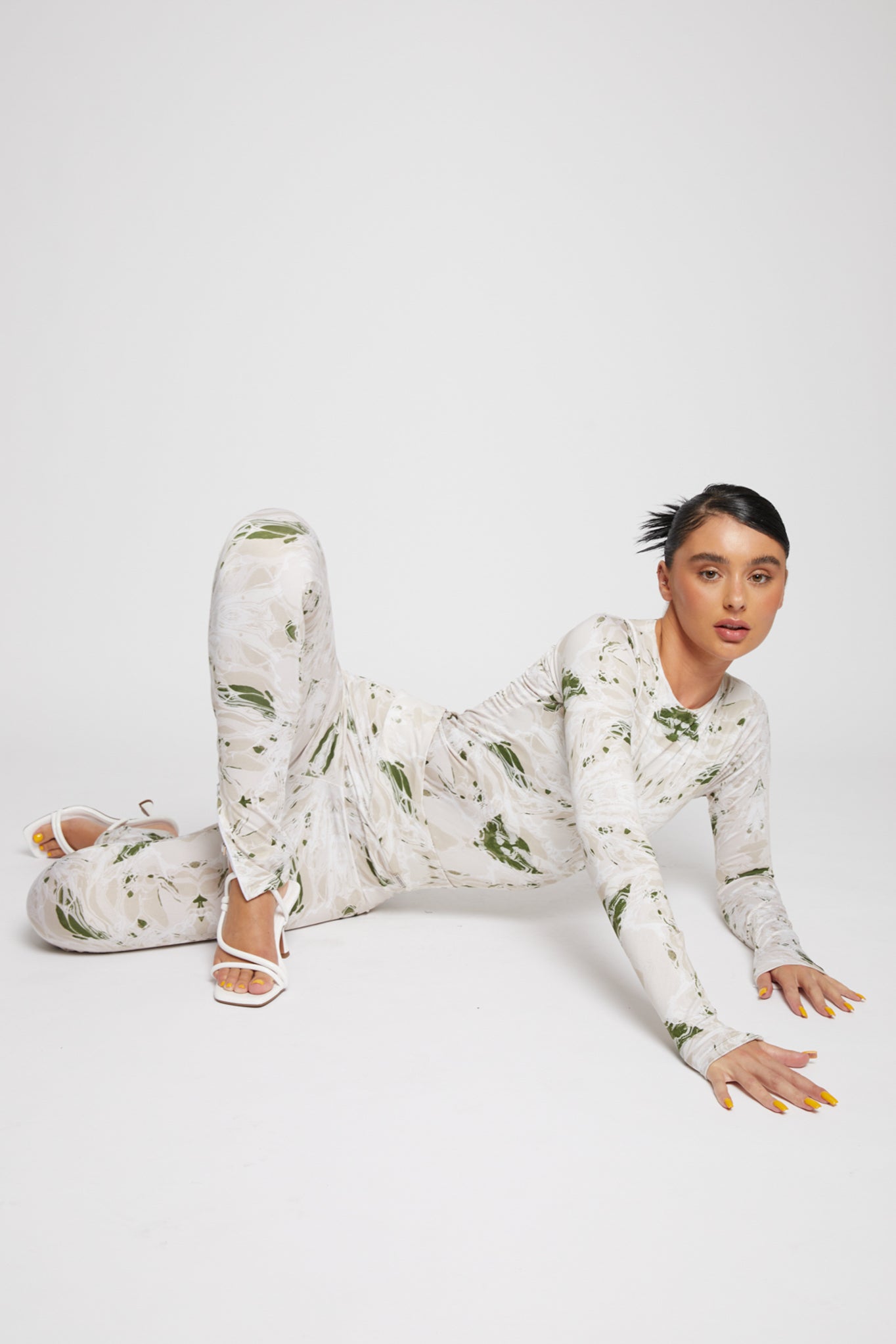 A model posing on the floor in the printed dipped waist leggings and top set.