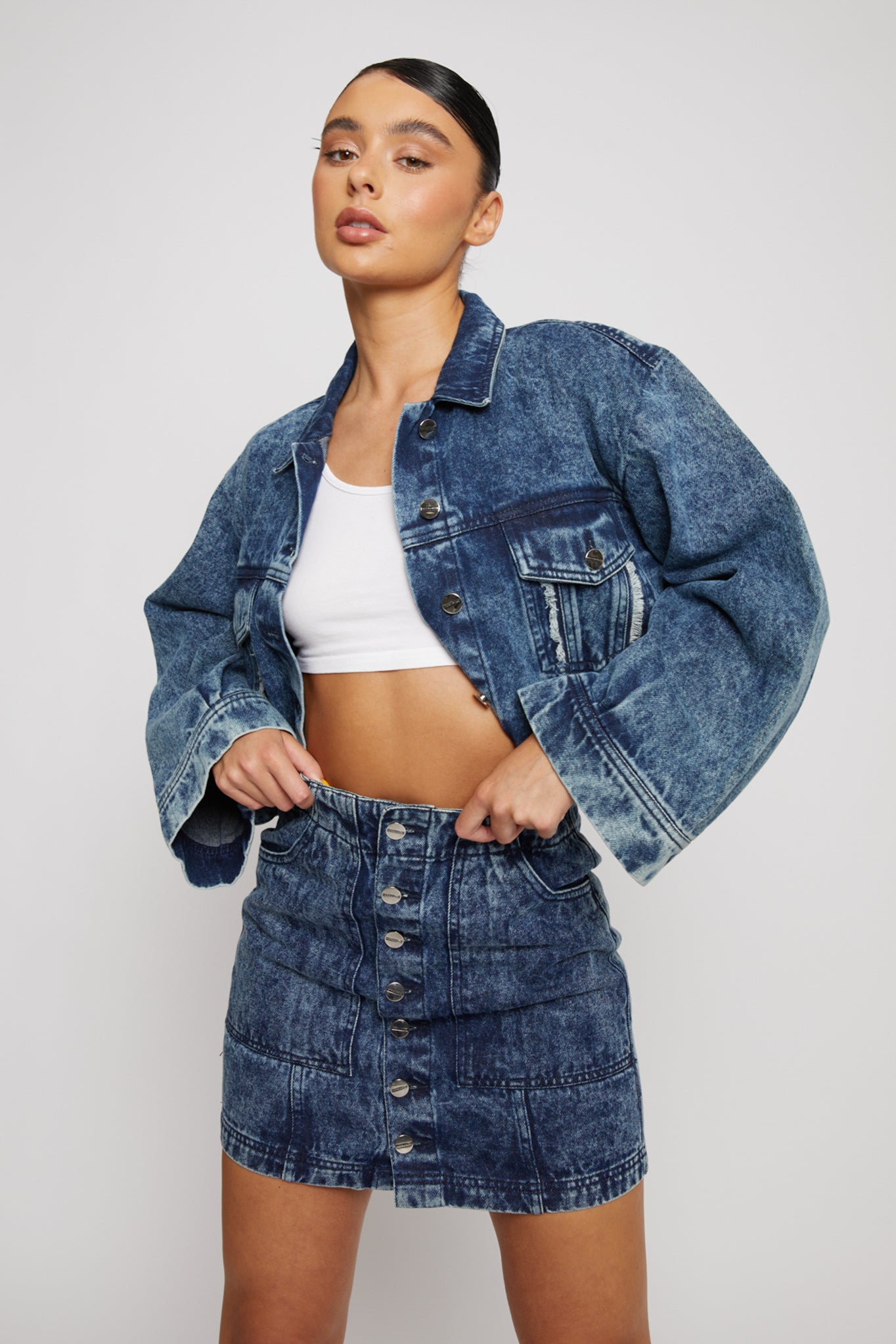 A model styled in the acid wash cropped denim jacket and matching skirt.