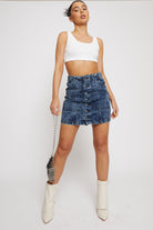 A model styling the acid wash denim skirt with a handbag and white boots