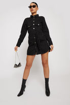 A model styling the women's black washed denim dress with sunglasses for a chic look