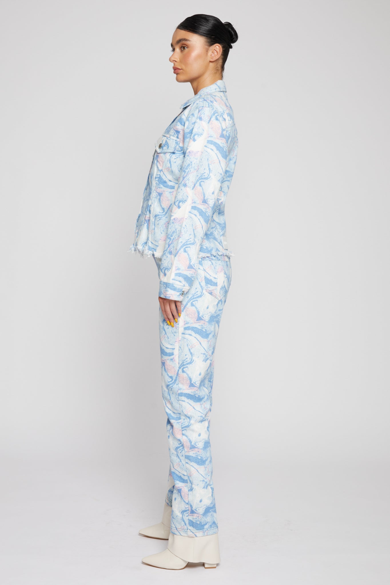 Side profile of a model showing the tapered waist fit of the psychedelic denim jacket.