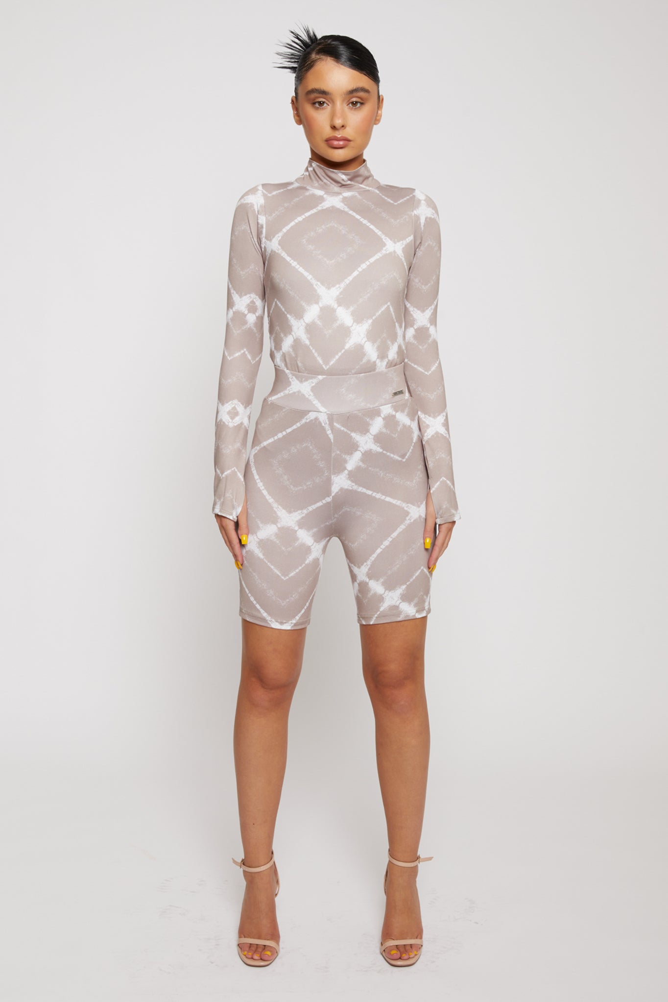 A model wearing the full taupe and white printed cycling shorts and long-sleeve top set.