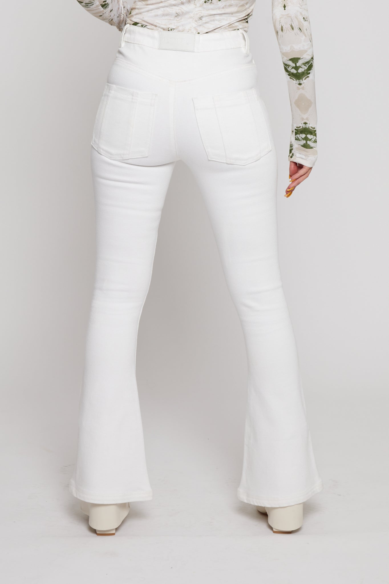 Close-up back view of the white stretch denim flare jeans.