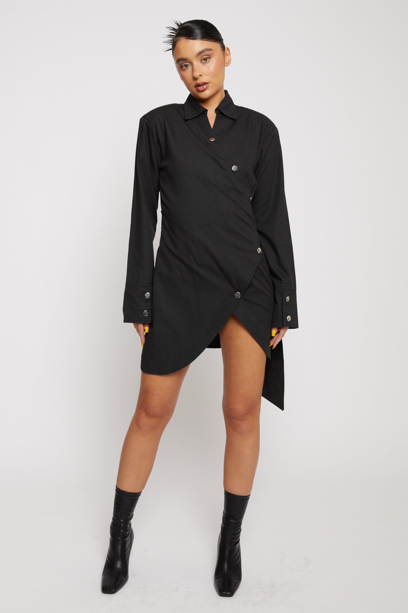 Front view of a model wearing the women's black cotton asymmetric shirt dress.
