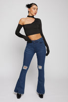 A model posing in the women's distressed flare jeans in a dark wash.