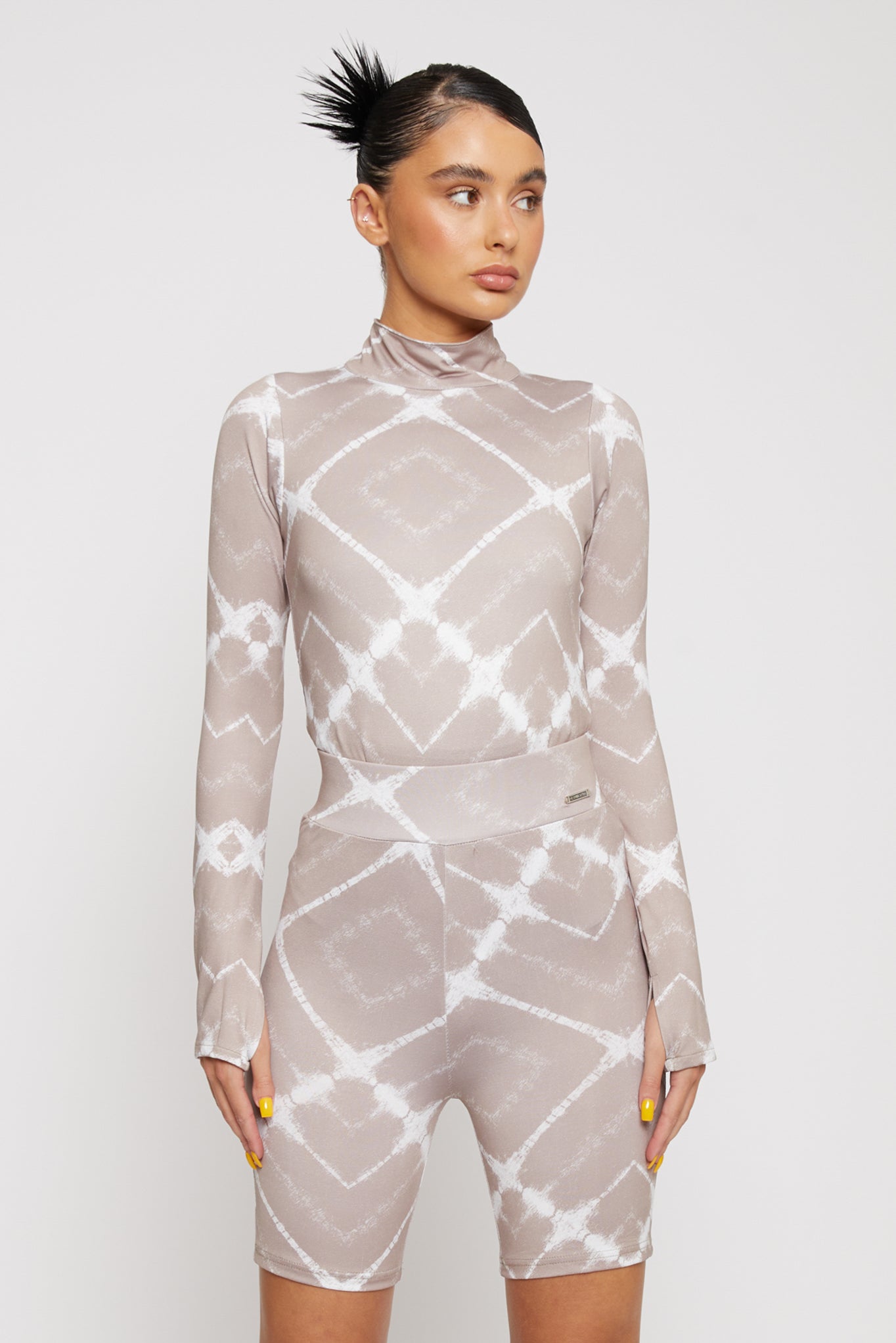 A model styled in the women's taupe cycling shorts and matching high-neck top.