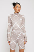 A model styled in the women's taupe cycling shorts and matching high-neck top.