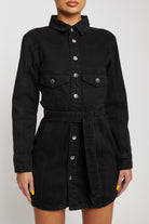 Close-up of the women's black washed denim dress, highlighting the chest pockets and tie belt
