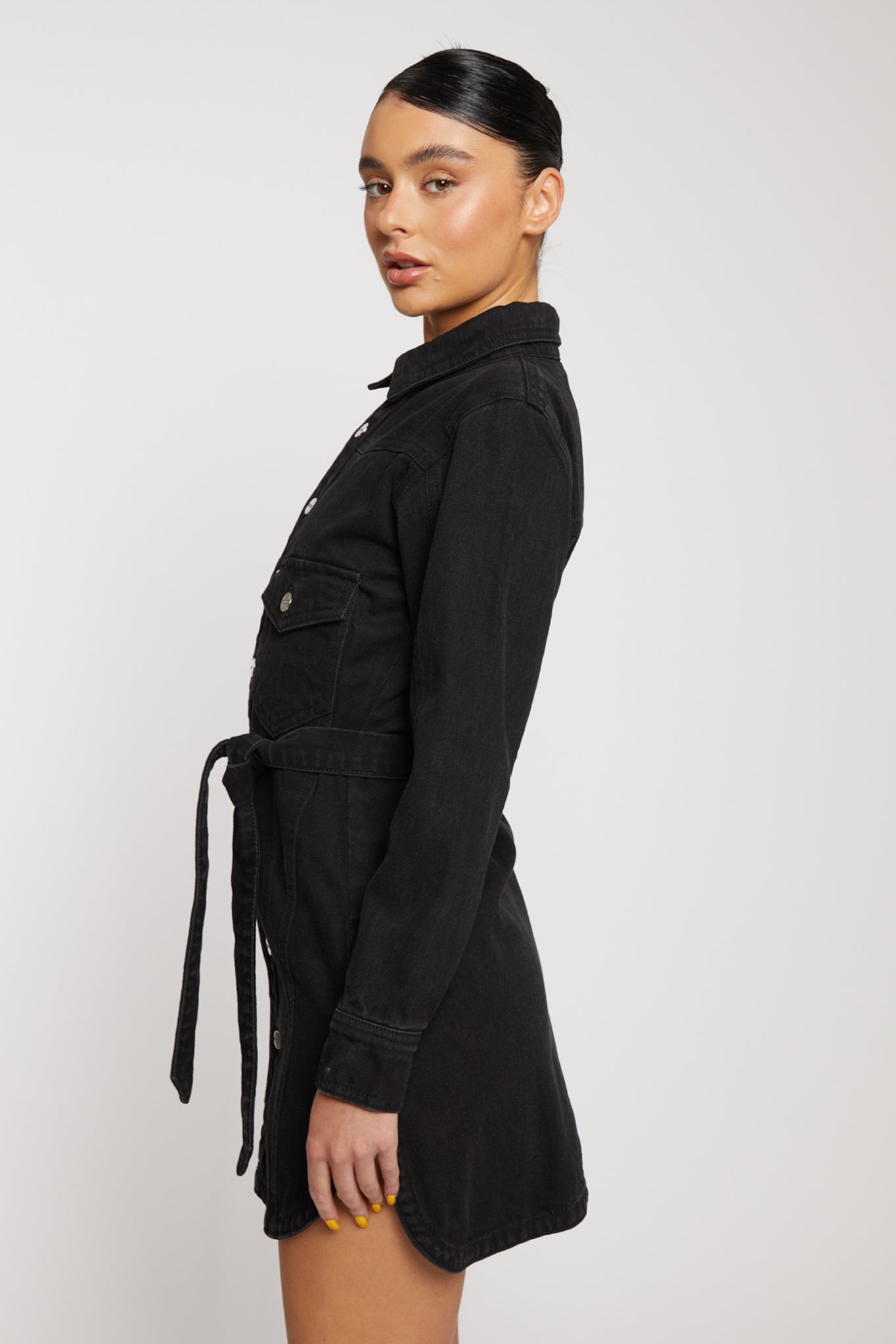 Side profile of a model showing the silhouette of the women's black denim dress