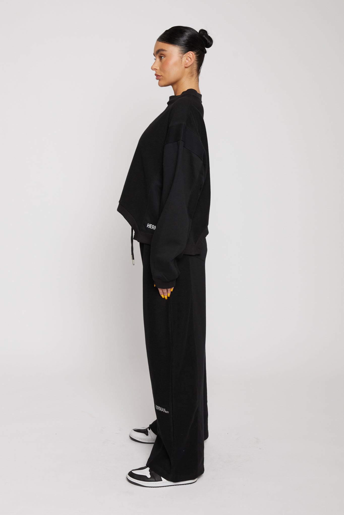 Model posing in a side angle wearing black kroen joggers womens showing the wide leg silhouette