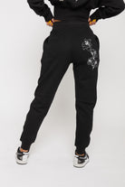 Back view of the women's black tapered joggers with white floral embroidery