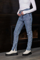 Side view of a model wearing women's blue acid wash jeans with an ankle zip
