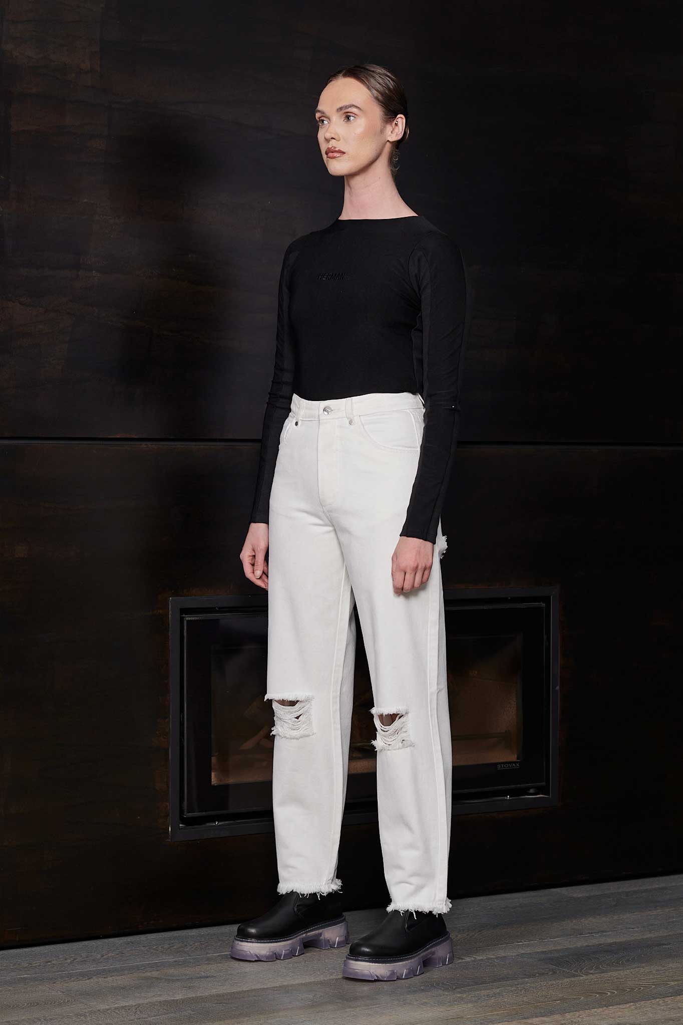 Side profile of a model wearing the off-white distressed tapered jeans.