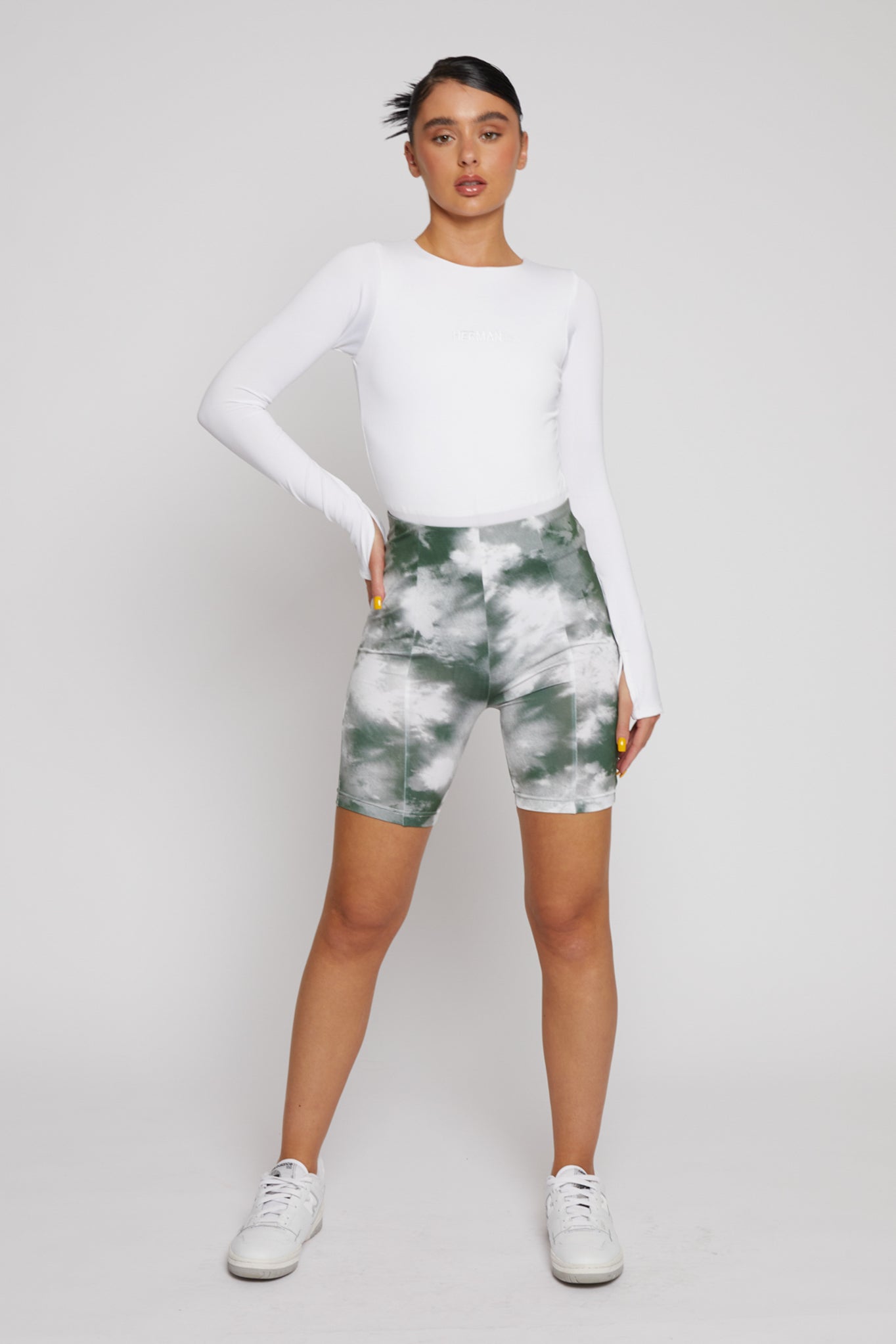 A model styled in the women's green tie-dye printed cycling shorts.