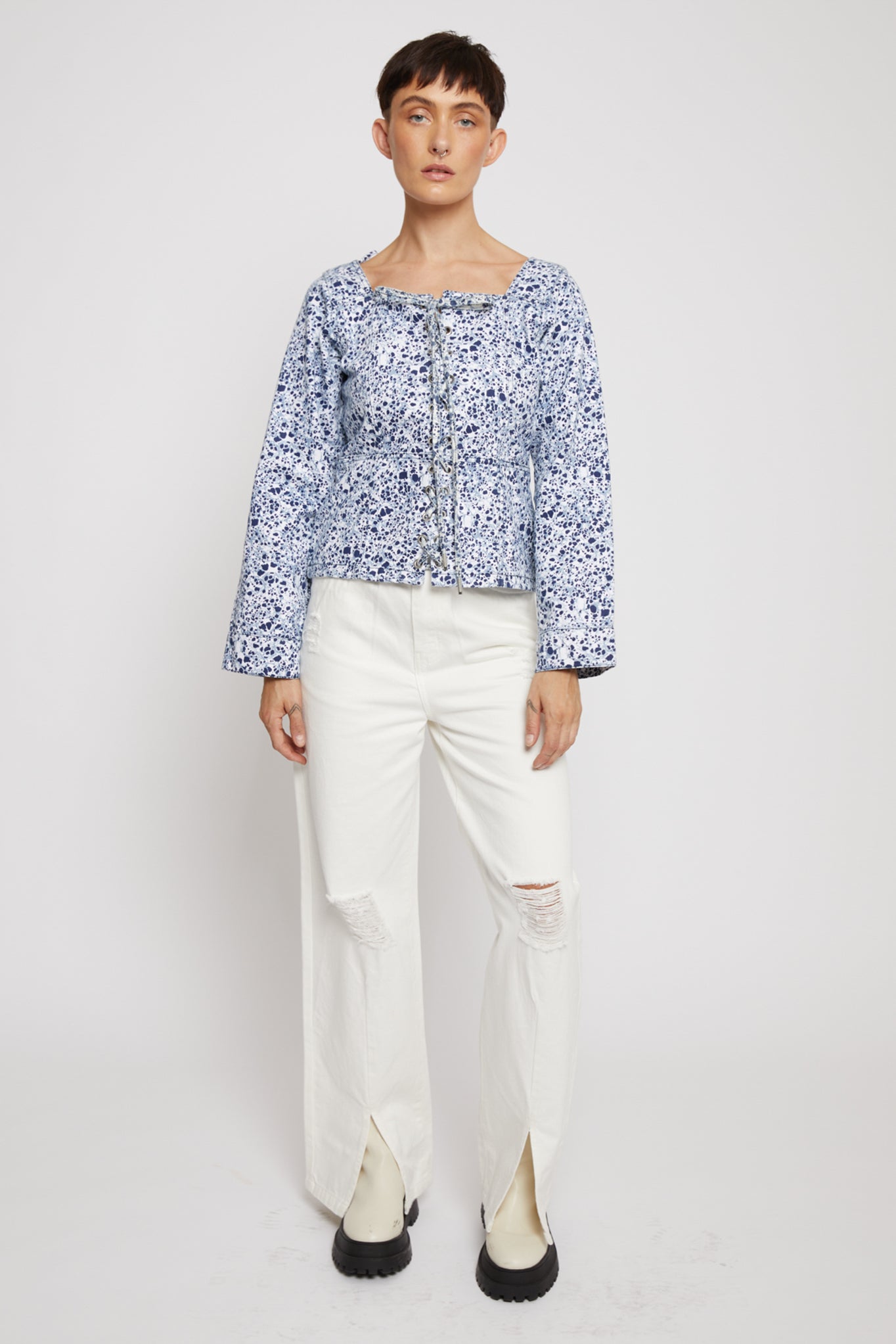 A model wearing the women's marble print lace-up top with white jeans.
