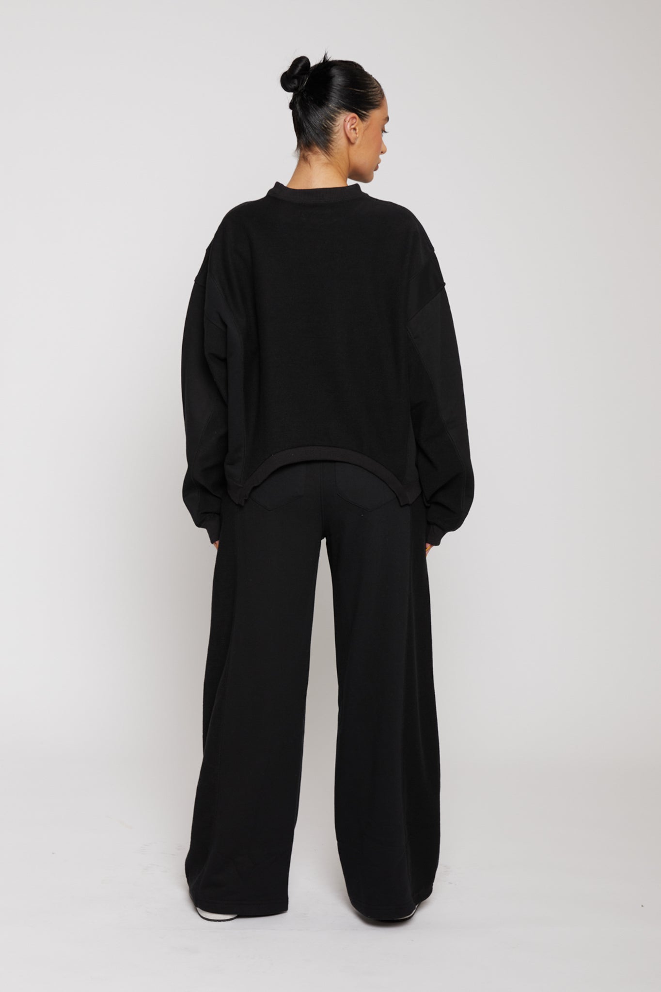 Rear full body view of model wearing stylish wide joggers in black